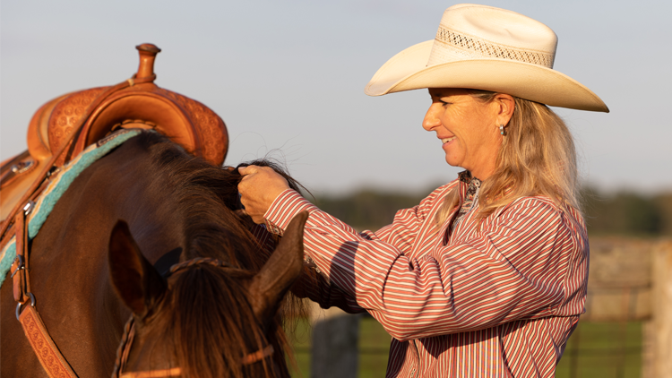 WPRA barrel racer Sherry Cervi adjusting the saddle on her horse.